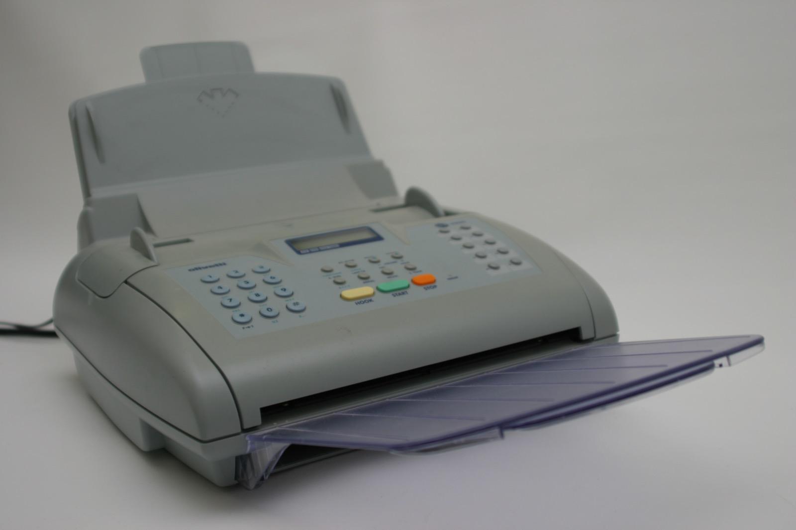 A telefax machine sitting on an office surface with paper loaded in the feeder