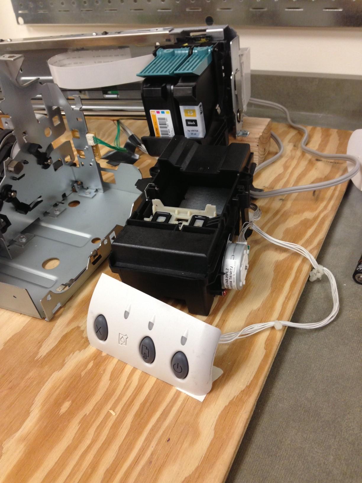 Close-up of an inkjet printer's print head, ink tray, and control panel with the cover removed