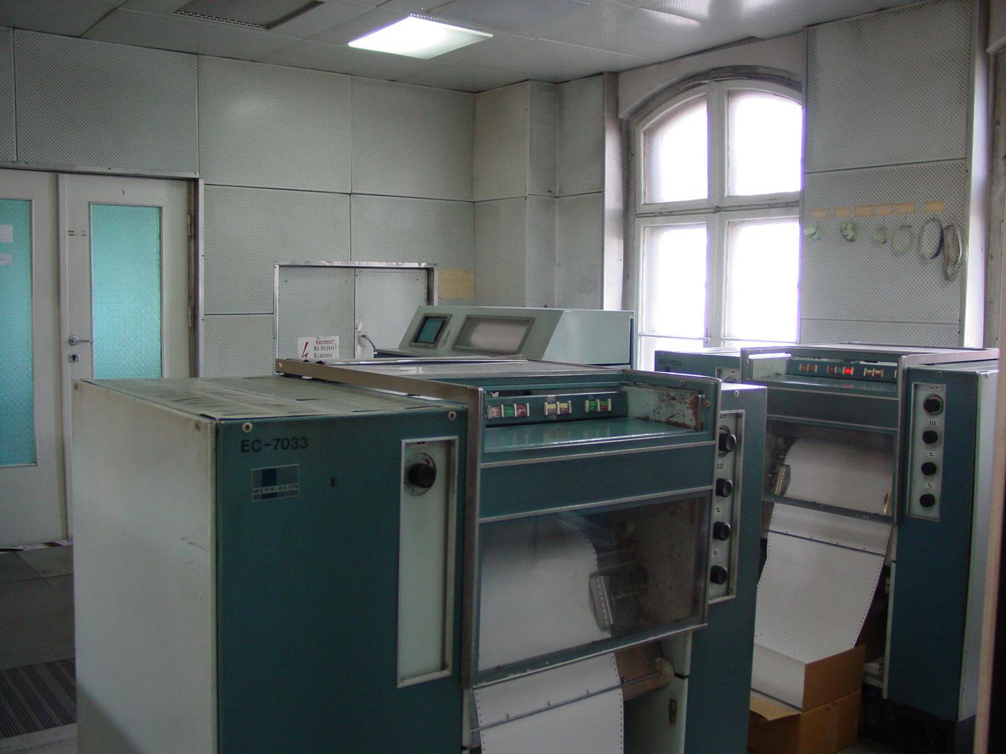 Several large line printers standing side by side in a computer centre machine room