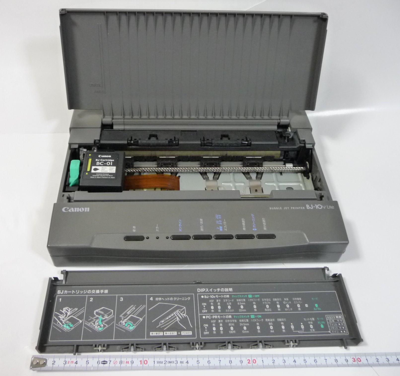 Canon BJ-10v Lite portable Bubble Jet printer photographed beside a ruler for scale, with its inner cover detached and placed in front