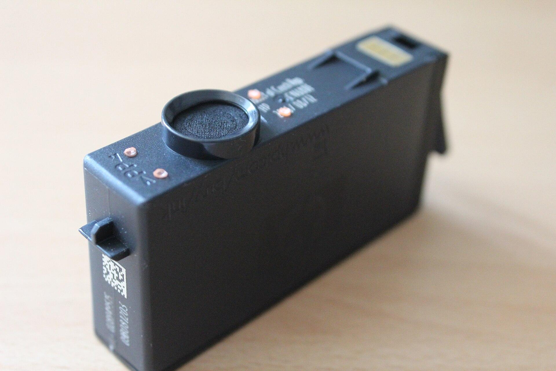 Underside of an inkjet cartridge showing a gold electrical contact pad at one end and the nozzle plate and chip area at the other