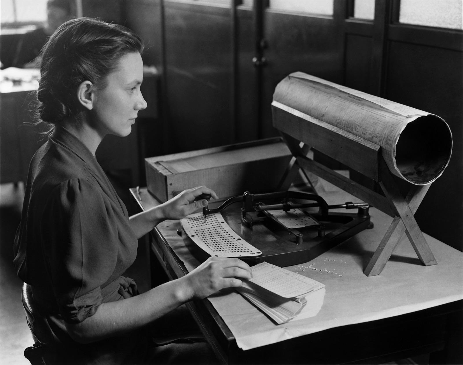 Black-and-white photograph of a 1940 US Census keypunch operator seated at a Hollerith pantograph machine with hands at the keys