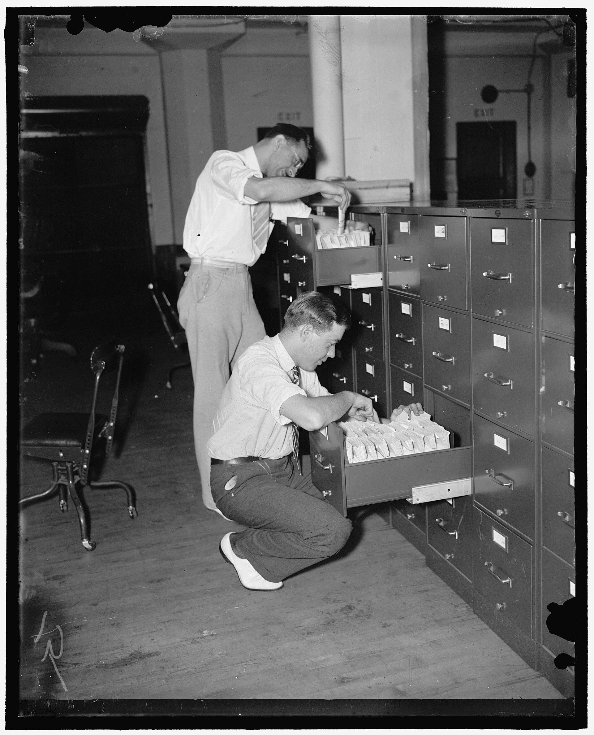 1938 photograph of a vast records office: rows of workers standing at long banks of filing units that stretch away down the room